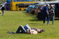 Two men lying on grass sleeping in sunshine at classic car event