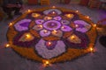 Two men make a mandala of flowers with burning candles in the evening of the festival of Diwali. Rangoli