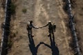 Two men in military uniforms shaking hands on dirt road. Generative AI Royalty Free Stock Photo