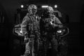 Two men in military uniforms stand in a hangar with a truck in the background. SWAT concept Royalty Free Stock Photo