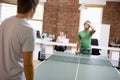 Two men in office space playing ping pong