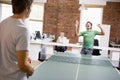 Two men in office space playing ping pong