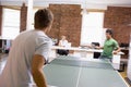 Two men in office space playing ping pong