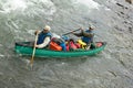 Two men in overloaded canoe on wild river rapids