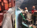 Two men painting the vessel in shipyard from high lift truck