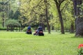 Two men in the park mowed grass mowers. Royalty Free Stock Photo