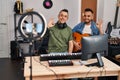 Two men playing classic guitar at music studio recording song doing ok sign with fingers, smiling friendly gesturing excellent Royalty Free Stock Photo