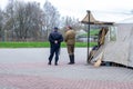 Two men in police and military uniforms of the old Soviet model stand with their backs to the camera.