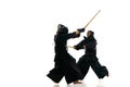 Two men, professional kendo athletes in uniform with helmet training with bamboo shinai sword against white studio Royalty Free Stock Photo