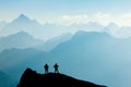 Two Men reaching summit after climbing and hiking enjoying freedom and looking towards mountains silhouettes panorama Royalty Free Stock Photo