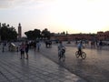 Two men ride bicycles as tourists stroll through Jemaa El Afna Square on a summer morning. Marrakesh. Morocco