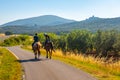 Two men are riding horses in tuscany countryside, Italy, with Capalbio skyline in background Royalty Free Stock Photo