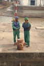Two men in safety helmets, vests and working clothes