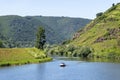 Two men are sailing a motorboat on a calm river between the hills covered with forest. Royalty Free Stock Photo