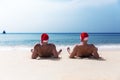 Two men in Santa Claus red hat sit on the beach in morning hangover Christmas holiday party dreams Royalty Free Stock Photo