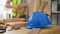 Two men shaking hands in a woodworking workshop with tools and a blue hardhat on the workbench Royalty Free Stock Photo