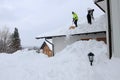 Two men shoveling high, heavy snow from a house roof Royalty Free Stock Photo
