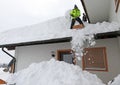 Two men shoveling high heavy snow from a house roof