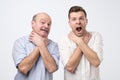 Two men showing choking gesture like they have problems with breathing.