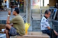 Two men sit back to back in a public square in Singapore Toa Payoh HDB estate