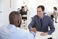 Two men sit and shake hands at a meeting in an office Royalty Free Stock Photo