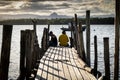 Two men sitting on the end of the wooden pier with the sunset in the background