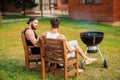 Two men sitting while preparing barbecue grill in park zone Royalty Free Stock Photo