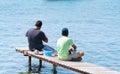 Two men sitting on small jetty fishing