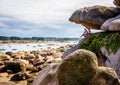 Two men sitting under a boulder are enjoying the view over the bay at low tide in Brittany, France