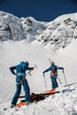 two men skiers in ski suits and helmets putting on hiking equipment for climbing Royalty Free Stock Photo