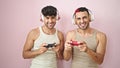 Two men smiling confident playing video game over isolated pink background Royalty Free Stock Photo