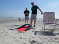 Two men smiling while playing a corn hole game on the beach by the ocean Royalty Free Stock Photo