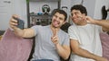 Two men smiling and posing for a selfie in a cozy indoor setting, expressing friendship and joy Royalty Free Stock Photo