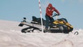 Two men with snowmobile talking on mountain sidehill