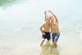 Two men standing together outdoors taking a selfie and smiling. Best friends taking a selfie while standing into the water of the Royalty Free Stock Photo