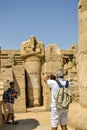 Two men take pictures on his smartphone of ancient ruins of Karnak temple. Tourists on excursion of famous Egyptian landmark