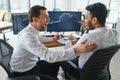 Two men traders sitting at desk at office together monitoring stocks data candle charts on screen analyzing price flow