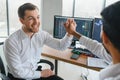 Two men traders sitting at desk at office together monitoring stocks data candle charts on screen analyzing price flow