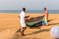 Two men with traditional Sinhalese costume cleaning up the tropical sand beach Royalty Free Stock Photo