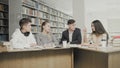 Two men and two women college students laughing while preparing for exams while sitting at table at university library Royalty Free Stock Photo