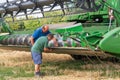 Two men undertaking basic maintenance on a stationary combine harvester. UK