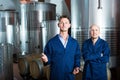 Two men in uniforms standing in winery fermentation compartment