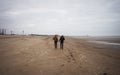 two men walk on the beach on a cold autumn day Royalty Free Stock Photo