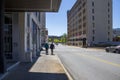 Two men walking along the sidewalk on Georgia Street with retail stores, restaurants and office buildings and cars driving