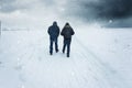 Two men walking along the snowy footpath in the stormy weather