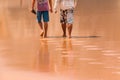 Two Men Walking on the Wet Sand Royalty Free Stock Photo