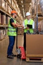 two men warehouse workers with hand pallet jack lift stand having talk, temwork