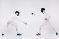 The two men wearing fencing suit practicing with sword against gray Royalty Free Stock Photo