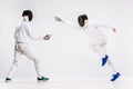 The two men wearing fencing suit practicing with sword against gray Royalty Free Stock Photo