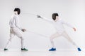 The two men wearing fencing suit practicing with sword against gray Royalty Free Stock Photo